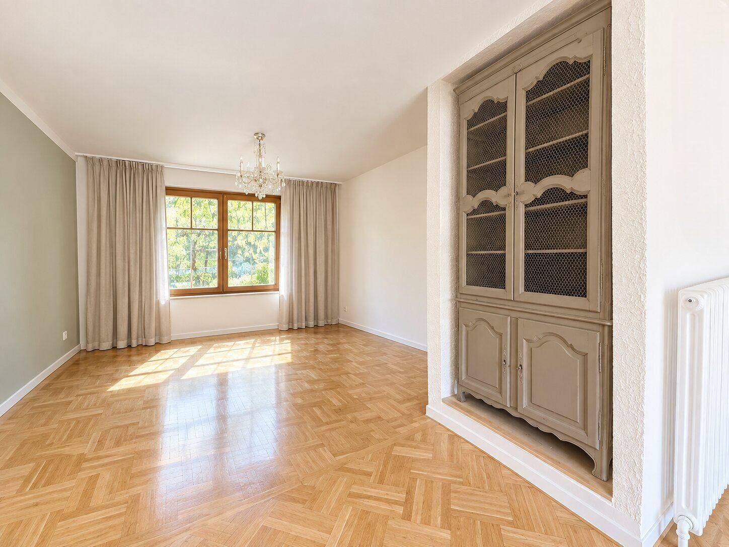 Geräumiges Zimmer mit Fischgrätparkett, großem Fenster und einem charmanten Einbauschrank.