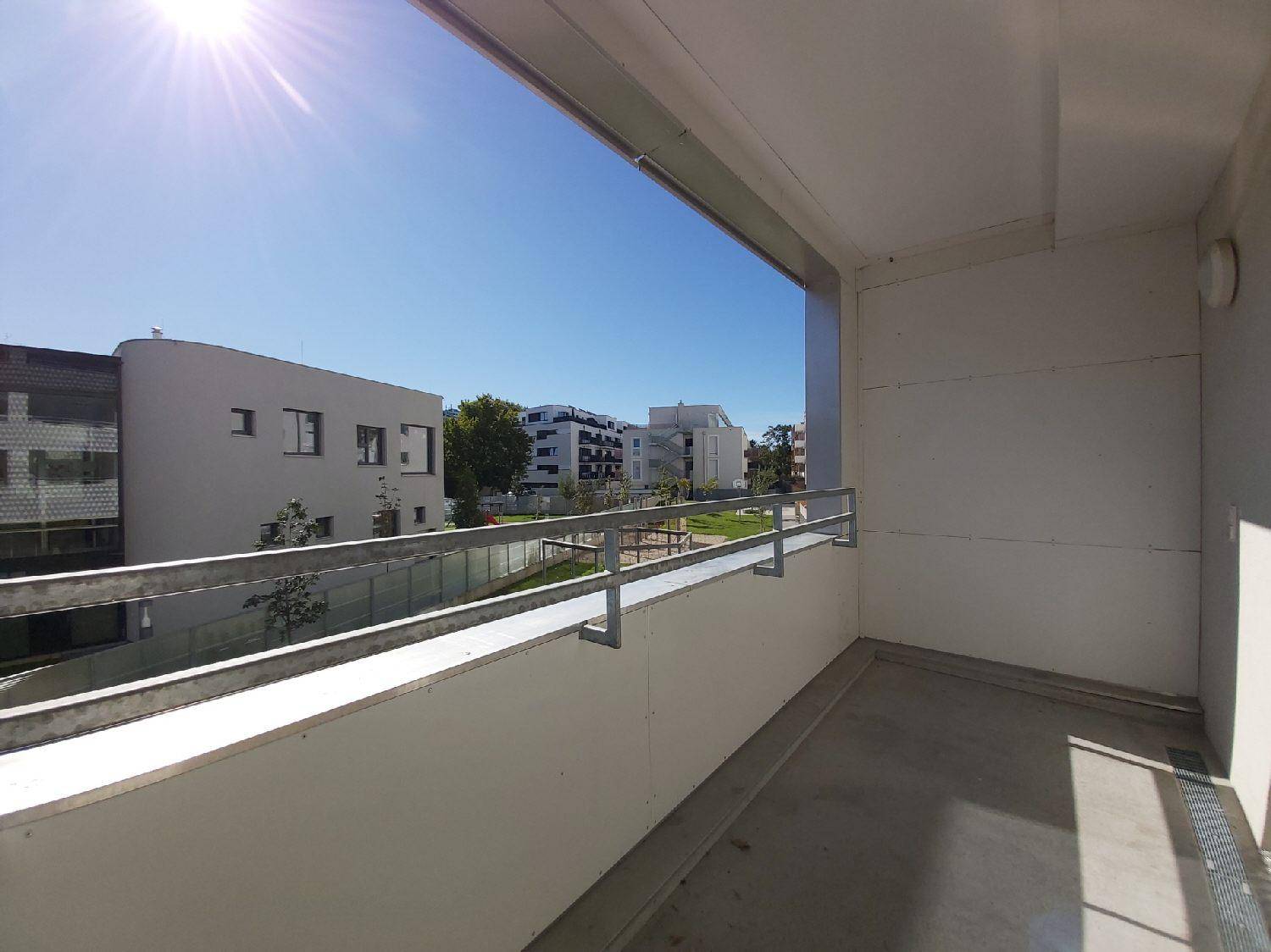 Sonniger Balkon mit Blick auf eine Grünfläche und weitere Wohngebäude.