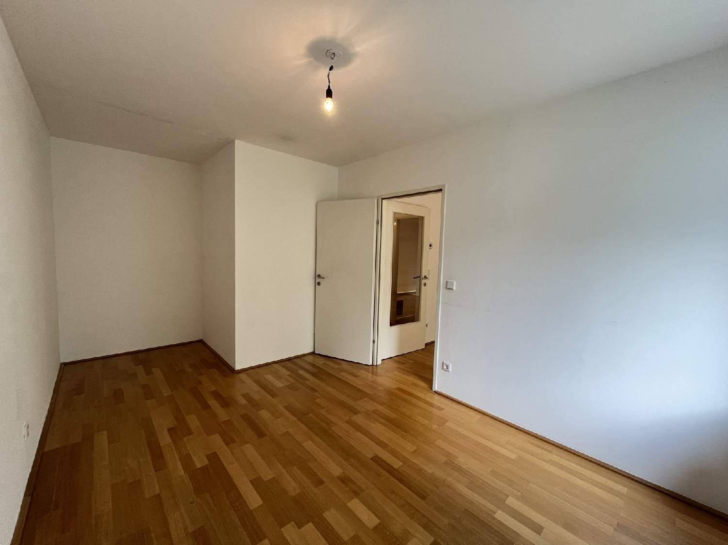 Leeres Zimmer mit hellem Parkettboden und weiß gestrichenen Wänden, bereit zur individuellen Gestaltung.