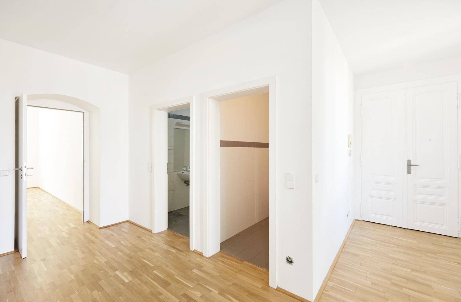 Heller Flur mit Parkettboden und Zugang zu verschiedenen Zimmern, inklusive einem Gäste-WC.