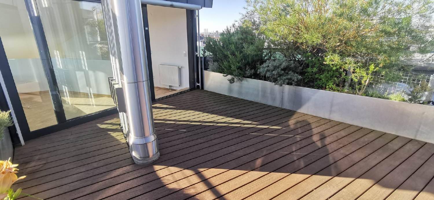 Sonnige Dachterrasse mit Holzplanken und Pflanzenkübeln, ideal zum Entspannen im Freien.