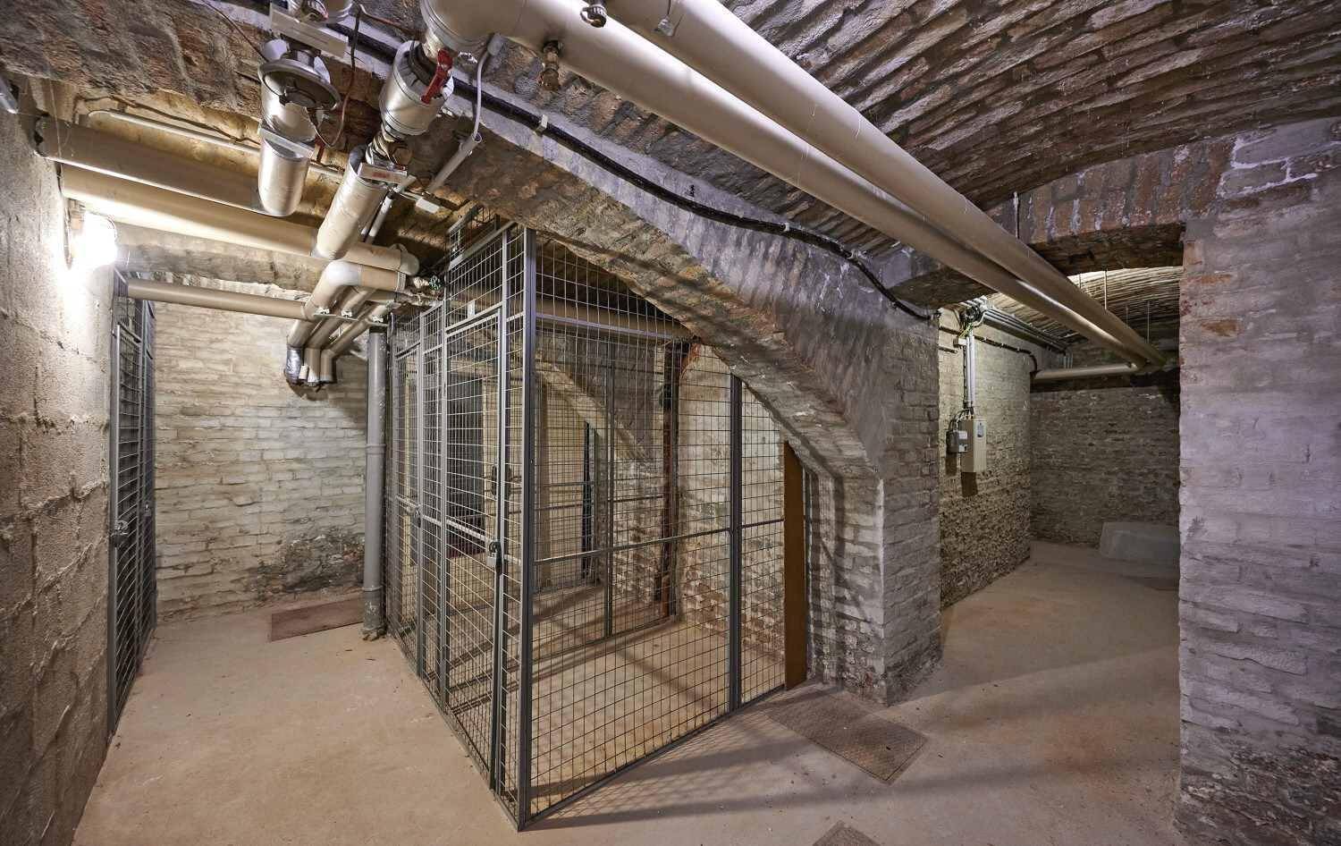 Historischer Kellerraum mit Ziegelwänden, Gewölbedecke und abschließbaren Lagerabteilen.