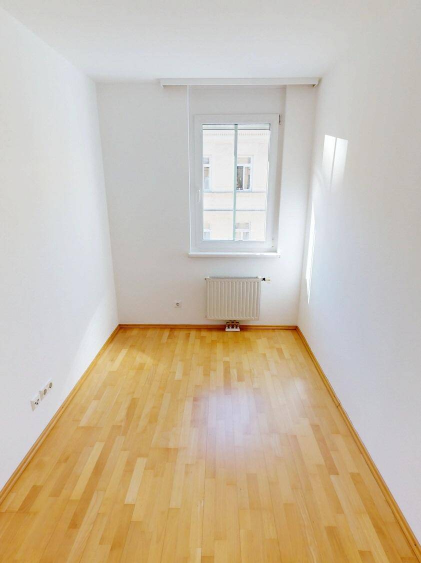 Kleines, helles Zimmer mit Parkettboden und einem Fenster, geeignet als Kinder- oder Gästezimmer.