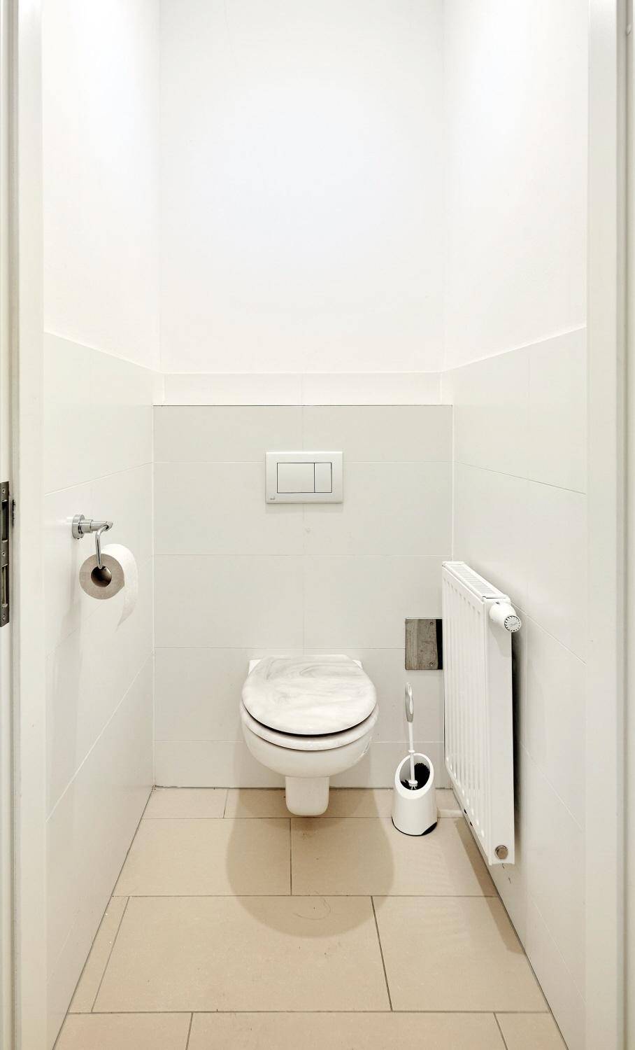 Separates WC mit wandhängender Toilette und Heizkörper, in hellem Design.