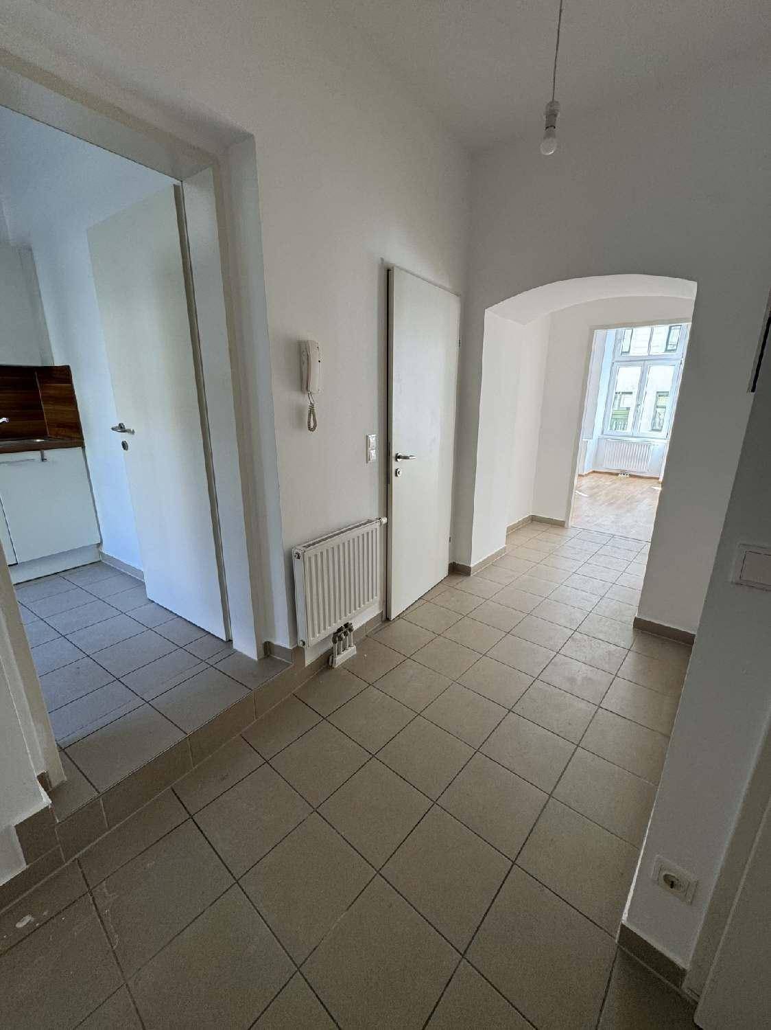 Heller Flur mit Fliesenboden, Gegensprechanlage und Zugang zu verschiedenen Räumen der Wohnung.