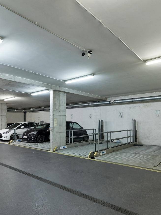 Blick in die Tiefgarage mit Parklifts und Überwachungskameras an der Decke.