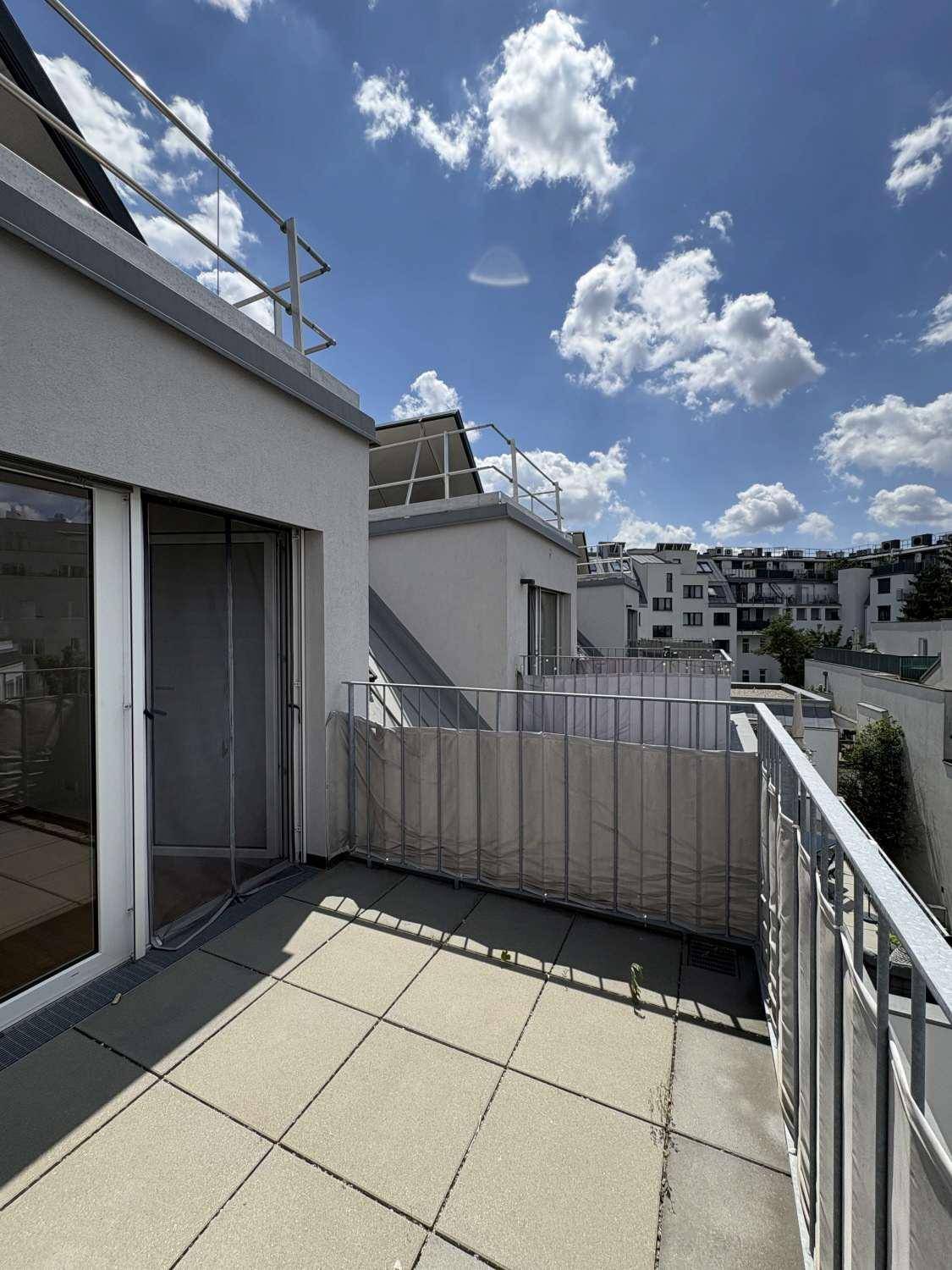 Helle Terrasse mit Fliesenboden und Zugang durch eine große Glastür, umgeben von Stadtansichten.
