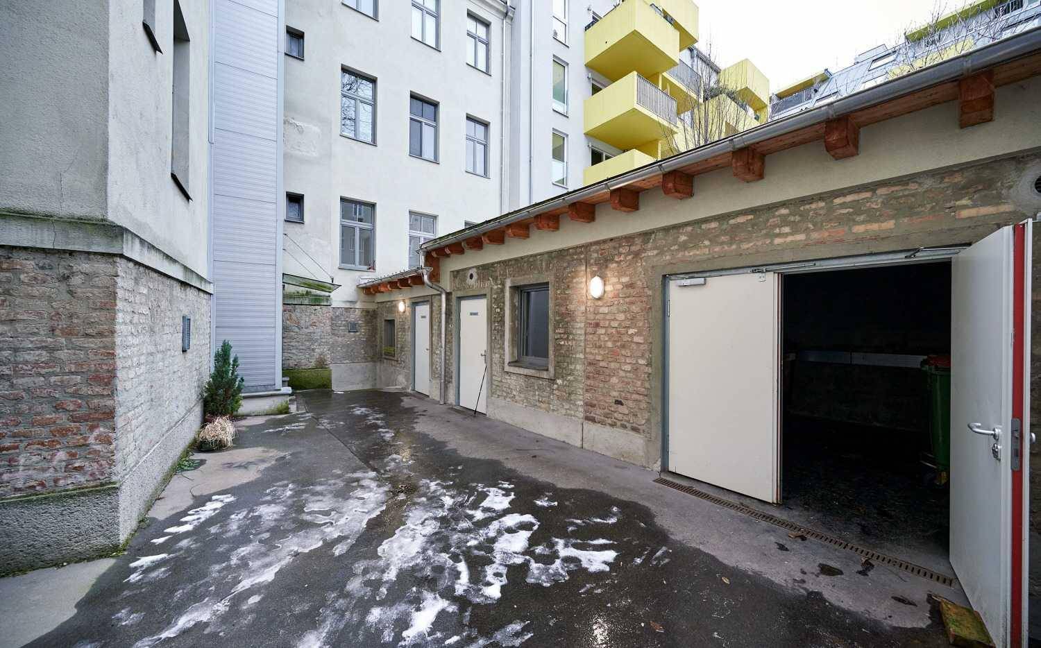 Hinterhof mit Garagen und Abstellräumen, umgeben von Gebäuden.