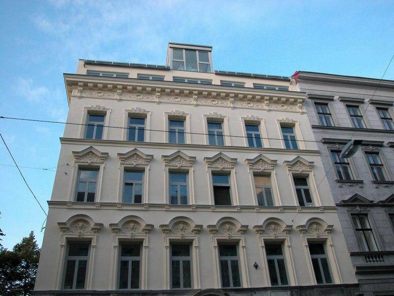 Elegante Fassade eines Altbaus mit detaillierten Verzierungen und modernem Dachausbau.