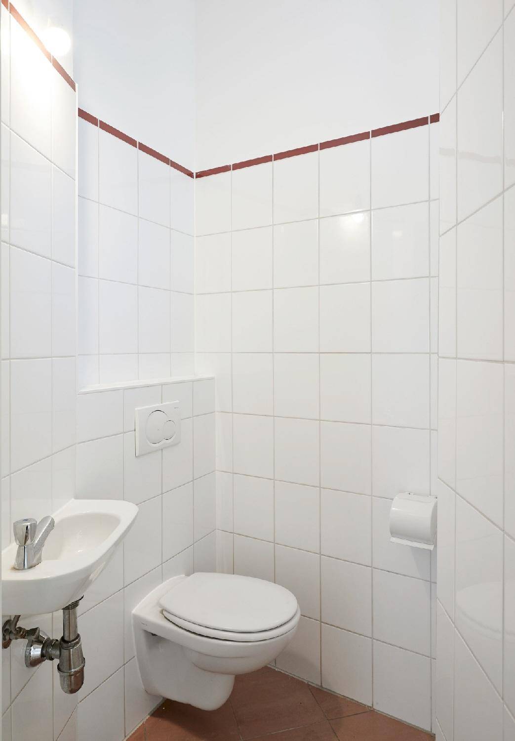 Kleines, gefliestes Gäste-WC mit Wand-WC und Handwaschbecken, in gutem Zustand.