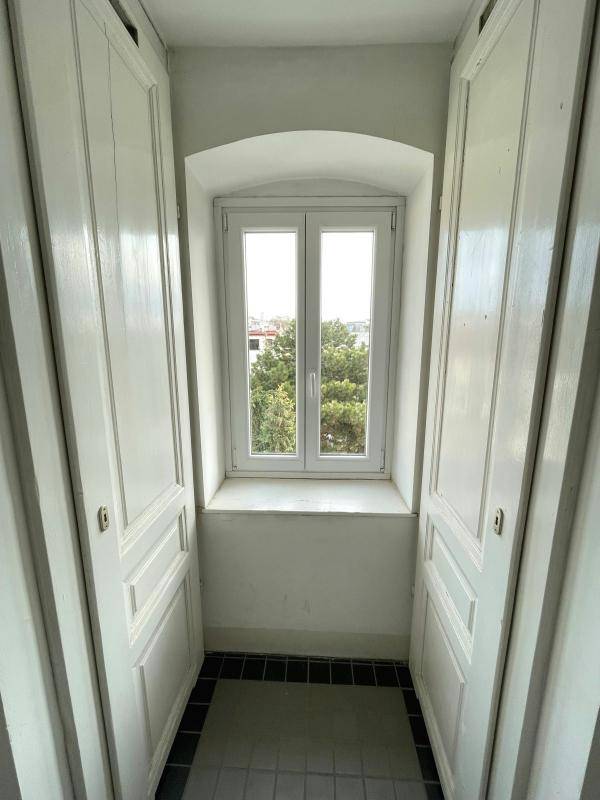 Heller Flur mit einem Fenster, das einen Blick ins Grüne bietet, und zwei weißen Schranktüren.