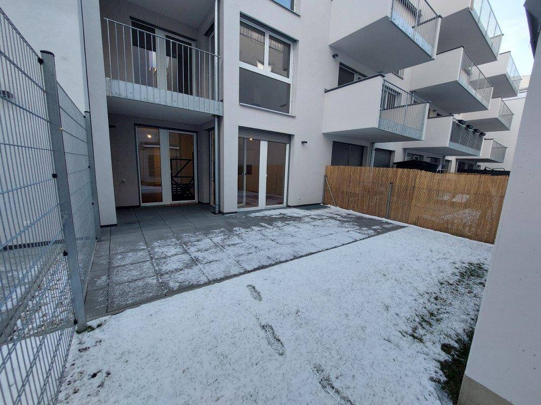 Terrasse mit angrenzendem Gartenbereich, teilweise mit Schnee bedeckt, und Zugang zu Innenräumen.