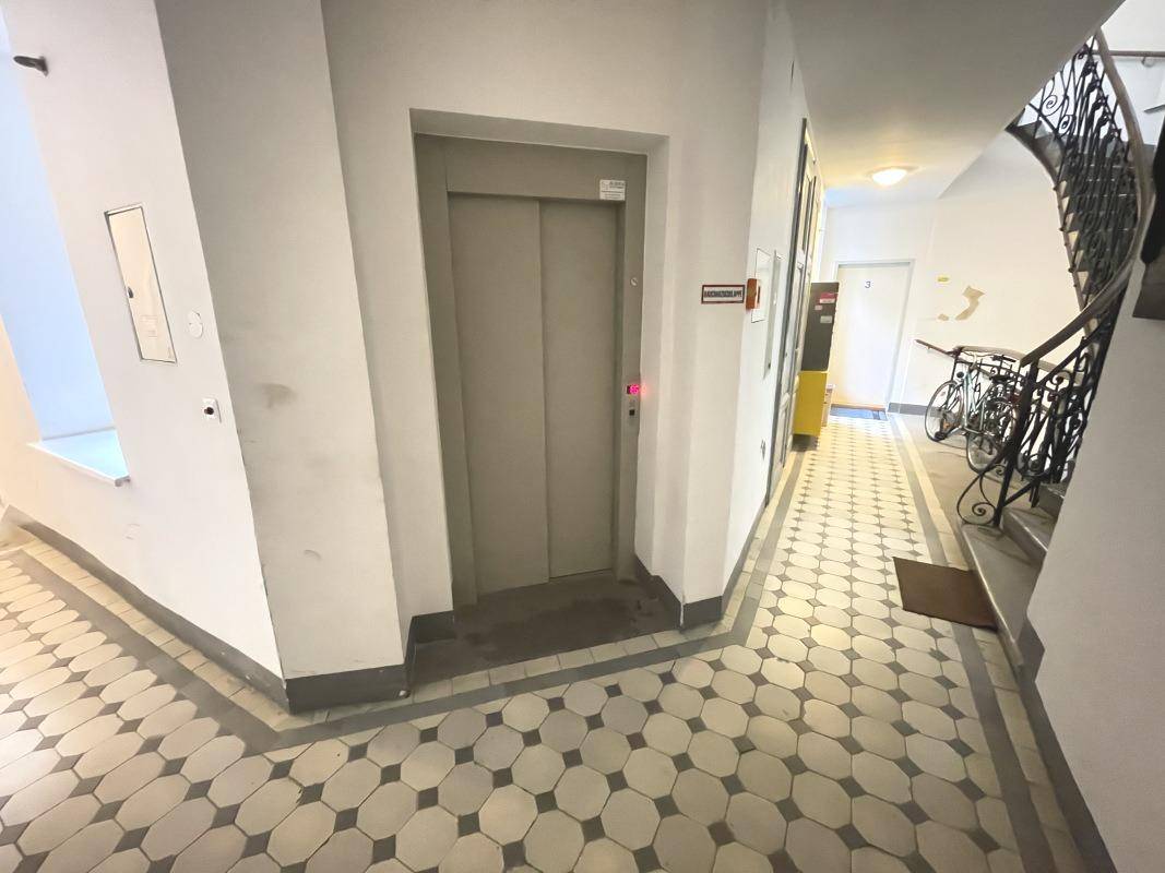 Treppenabsatz mit Aufzug, gemustertem Fliesenboden und Zugang zum Treppenhaus.
