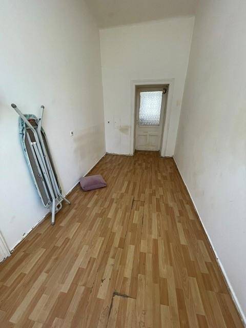 Leerer Raum mit Laminatboden und einer Tür, die zu einem weiteren Bereich führt.