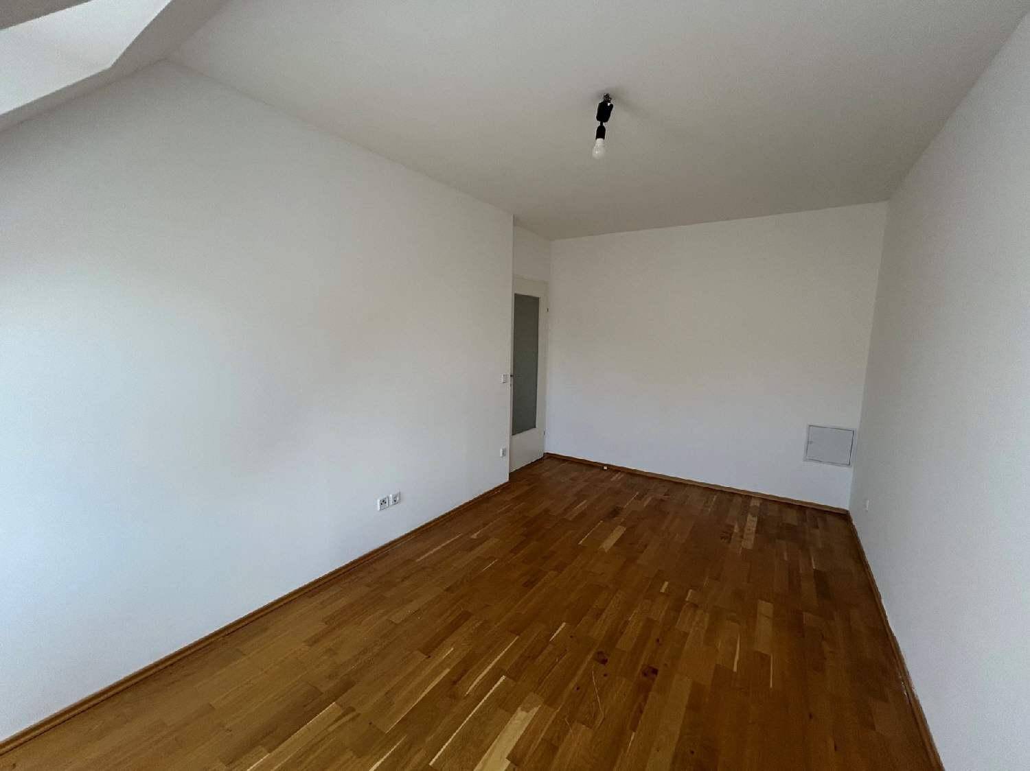 Geräumiges Zimmer im Dachgeschoss mit Holzboden und weißen Wänden, ideal als Schlaf- oder Arbeitszimmer.