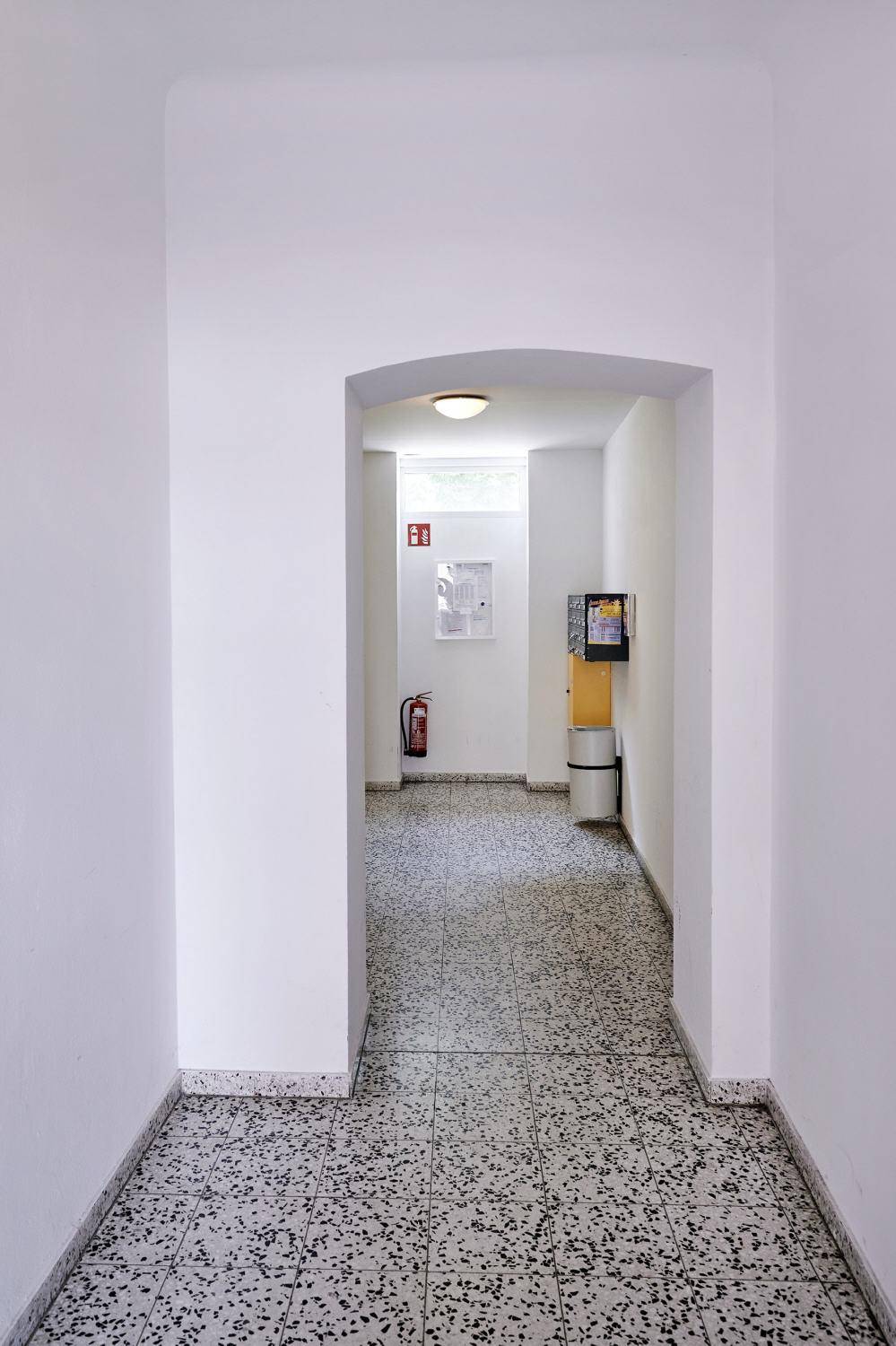 Heller Flur mit Fliesenboden und einem bogenförmigen Durchgang.