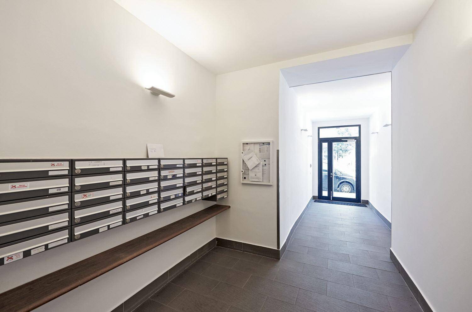 Langer Flur mit Briefkästen und Zugang zum Eingangsbereich des Gebäudes.