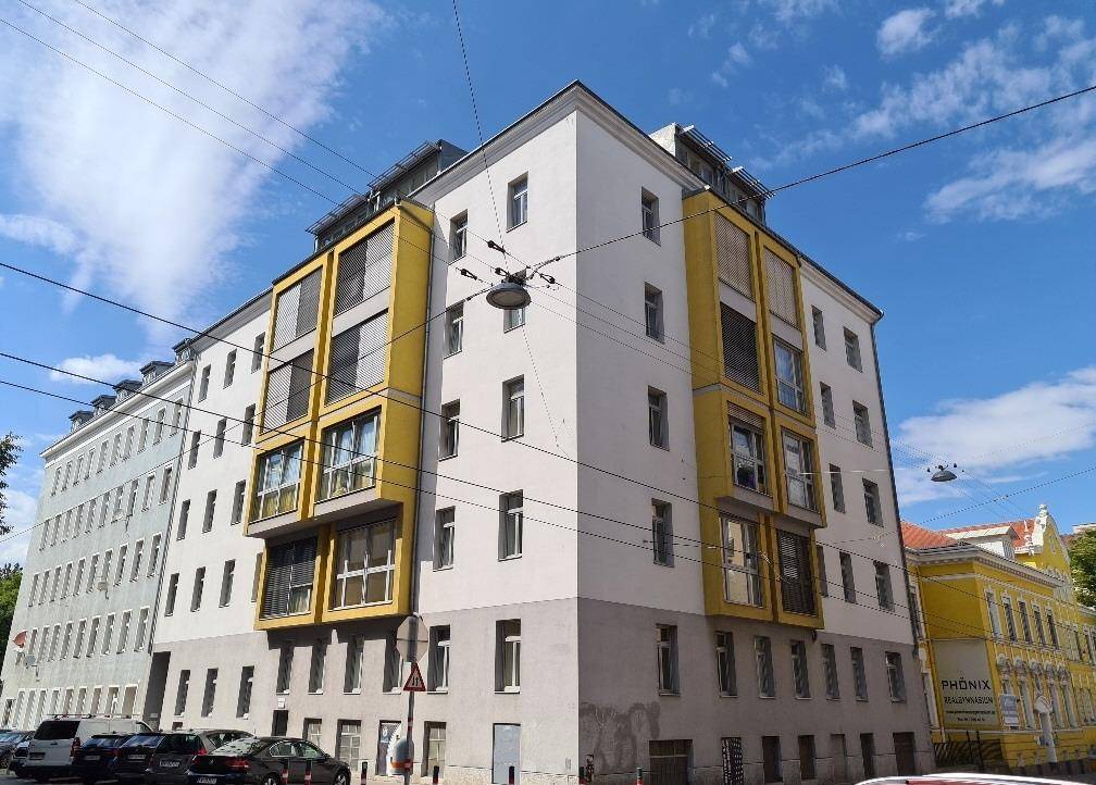 Wohngebäude mit markanten gelben Fassadenelementen und vielen Fenstern in urbaner Umgebung.