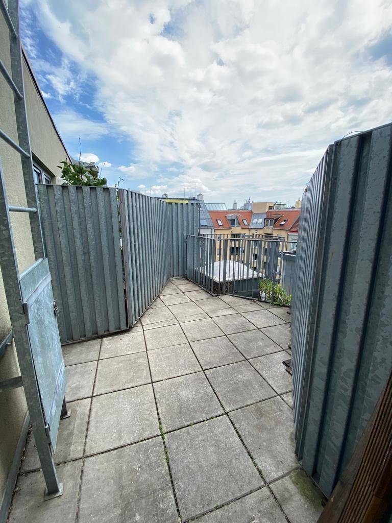 Dachterrasse mit Fliesenboden und Metallabtrennungen, bietet einen weiten Blick über die Stadt.