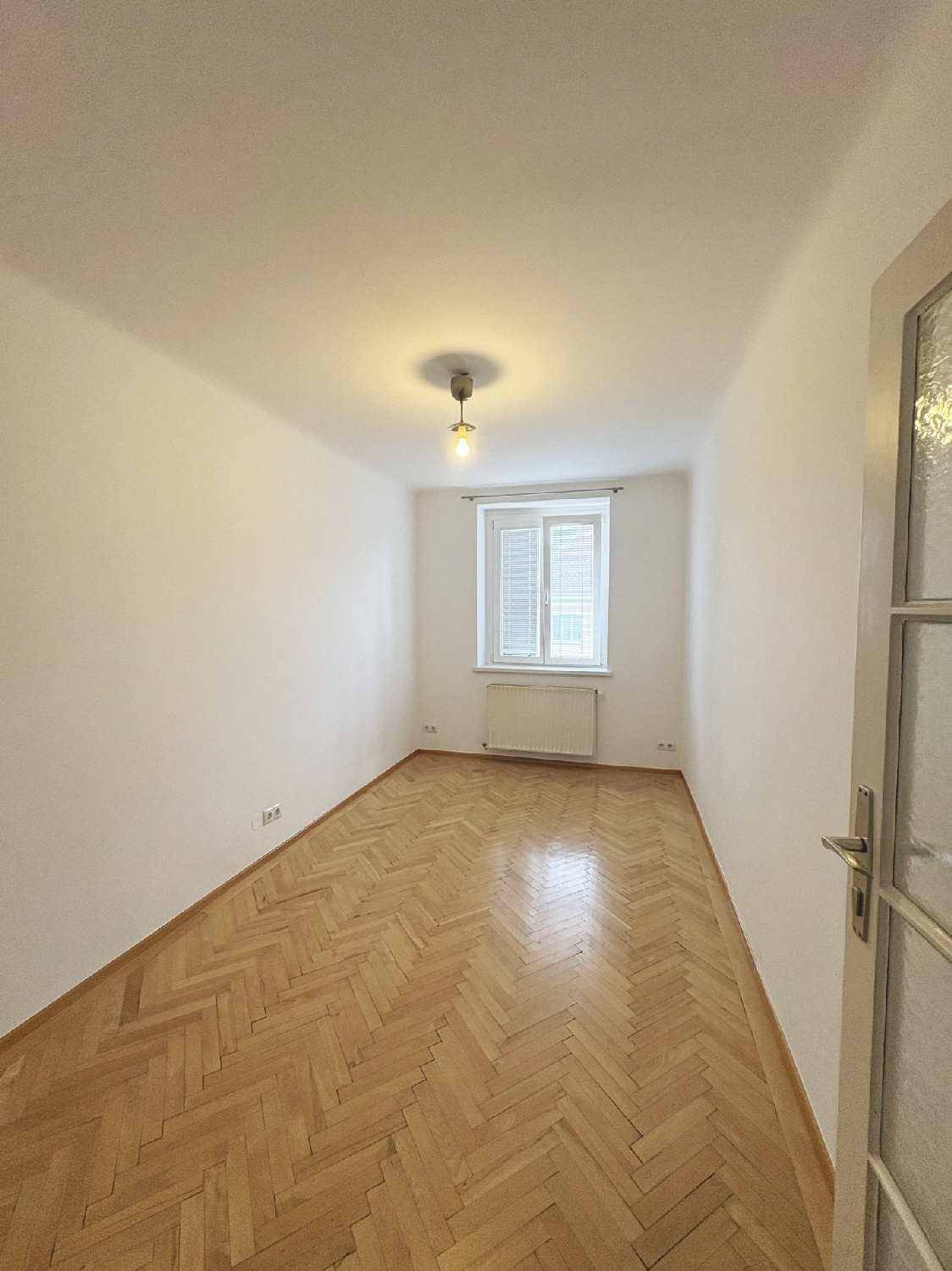 Gemütliches Zimmer mit Fischgrätparkett und Fenster mit Fensterläden.