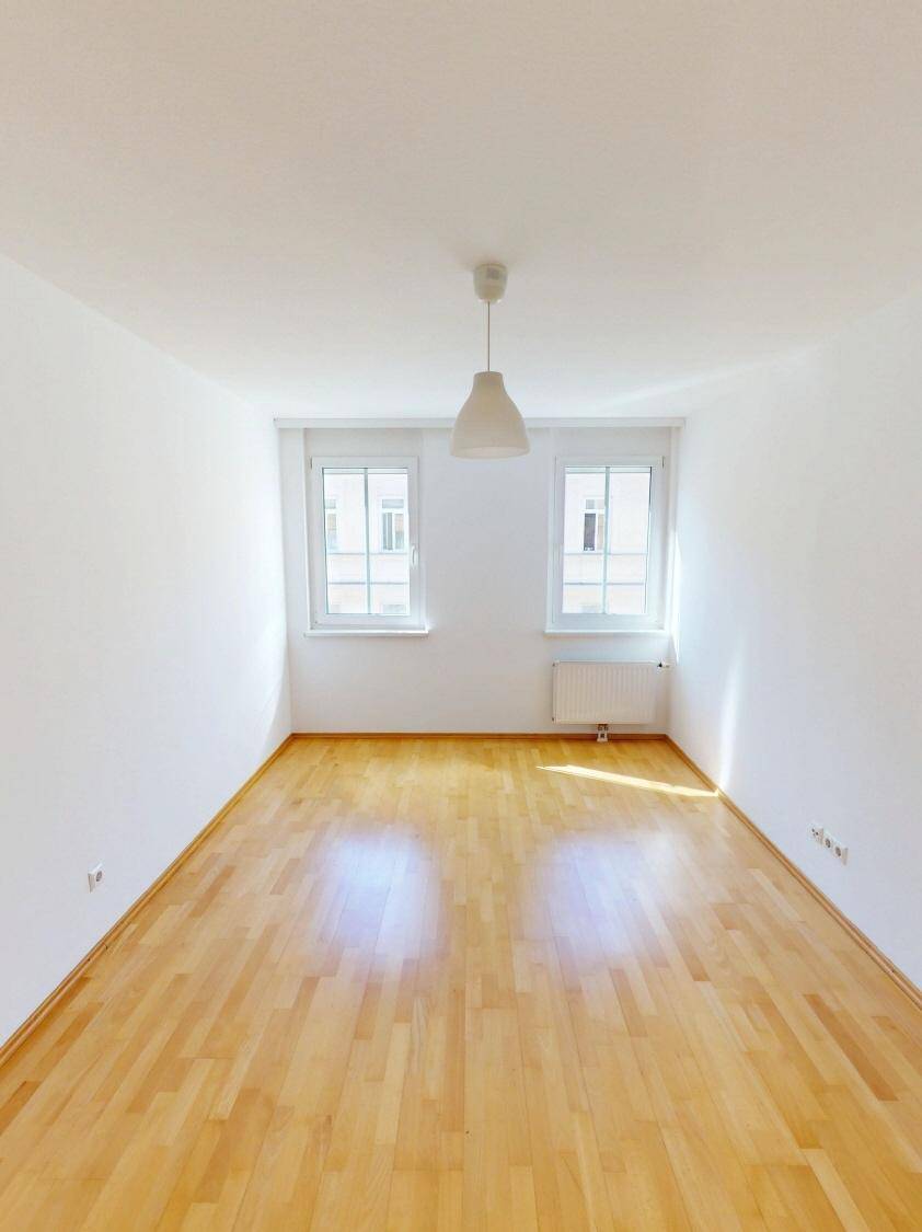 Helles Zimmer mit Parkettboden und zwei Fenstern, ideal als Schlaf- oder Arbeitszimmer.
