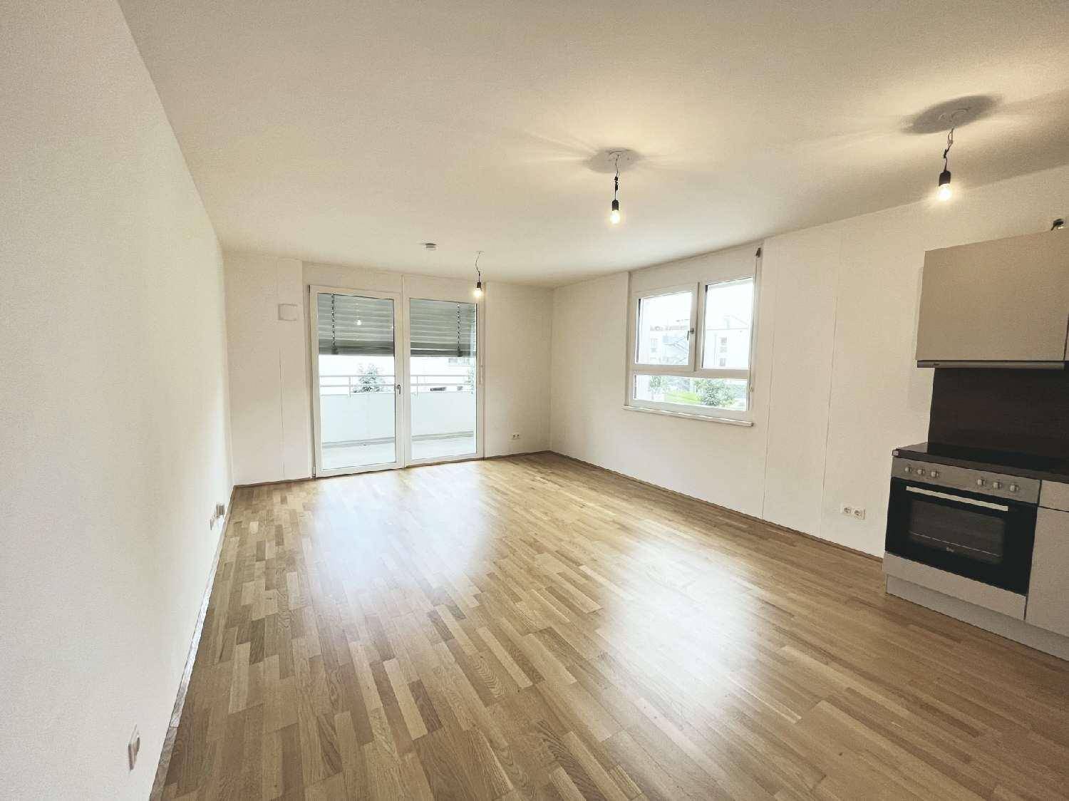 Geräumiges Wohnzimmer mit Parkettboden und Zugang zu einem sonnigen Balkon.