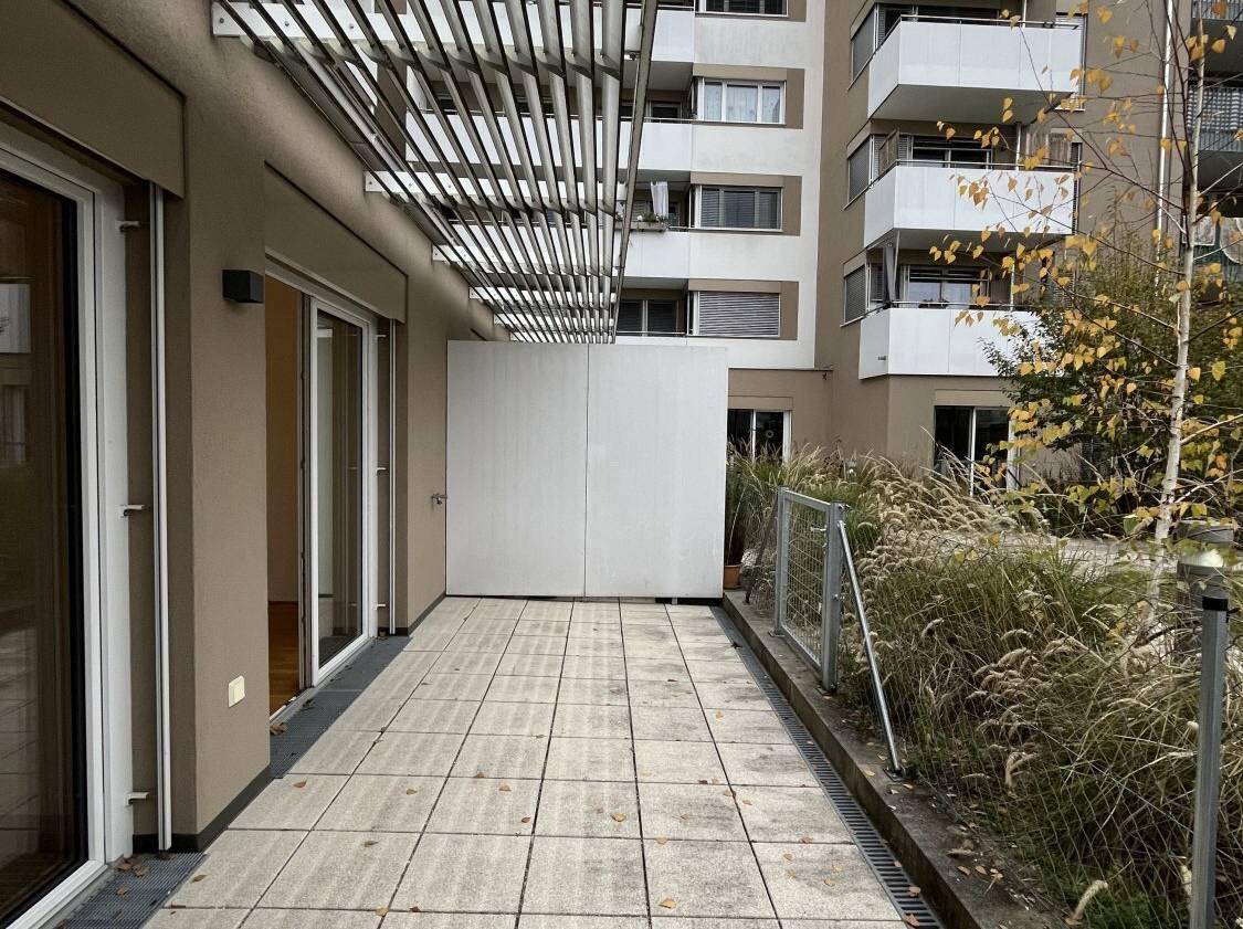 Große, geflieste Terrasse mit Lamellenüberdachung und Blick auf die Umgebung.