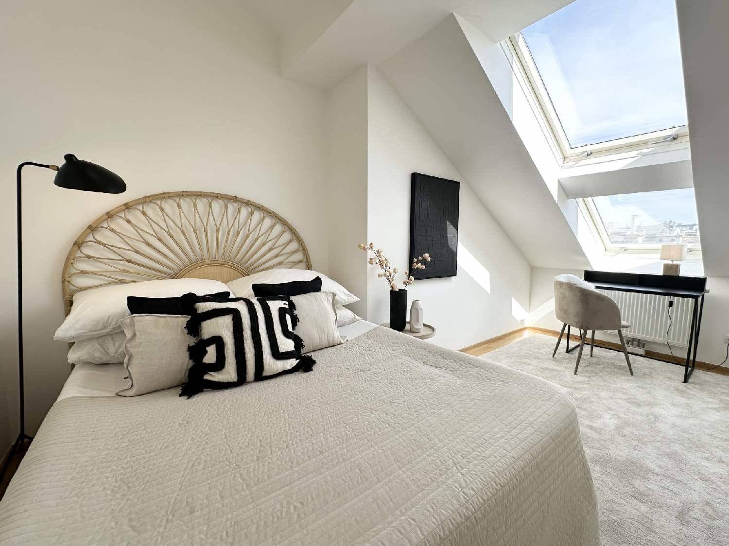Helles Schlafzimmer im Dachgeschoss mit großem Dachfenster, Schreibtisch und modernem Bett.