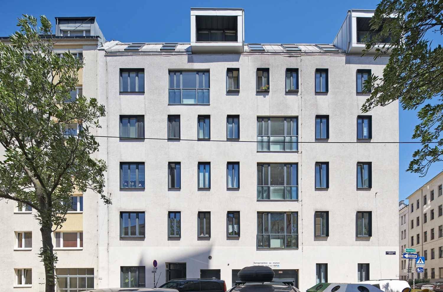 Fassade eines modernen Wohngebäudes mit zahlreichen Fenstern und Dachaufbauten.