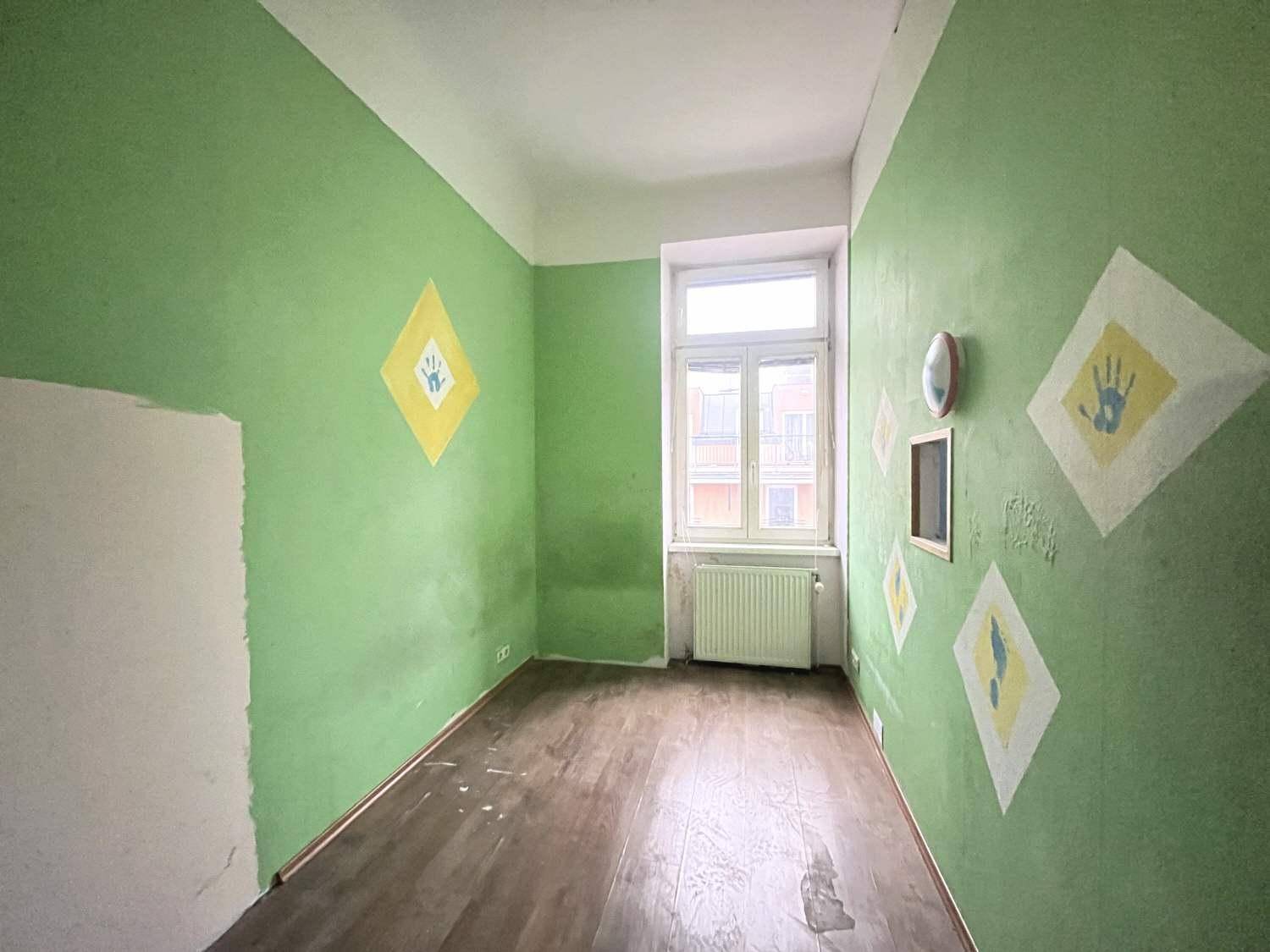 Kinderzimmer mit grünen Wänden, Holzboden und spielerischen Handabdruck-Dekorationen.
