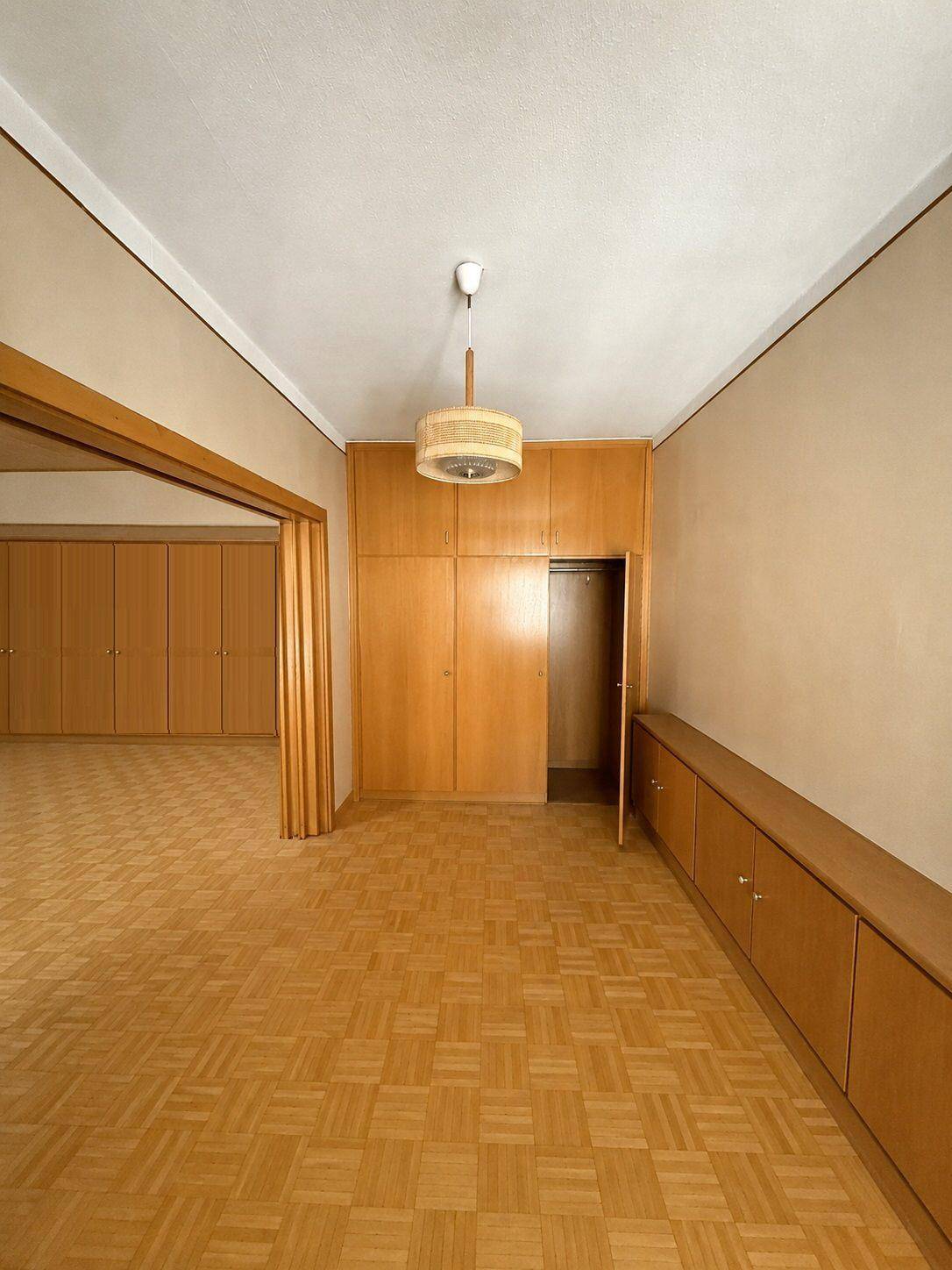 Geräumiger Raum mit Parkettboden und integrierten Holzschränken, der viel Stauraum bietet.