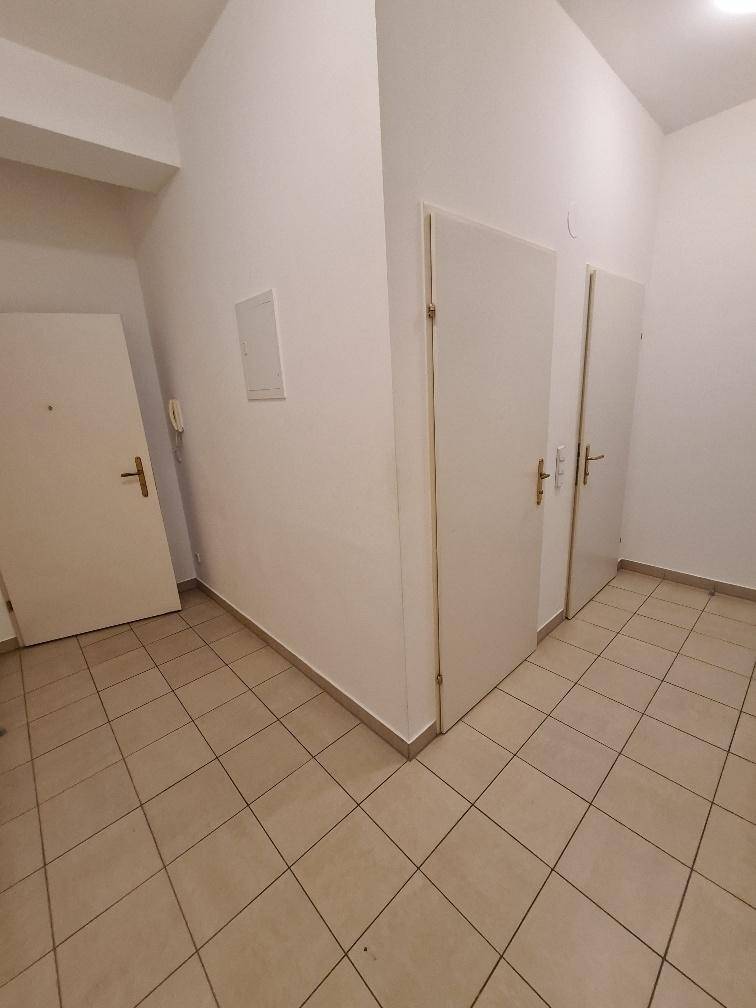 Eingangsbereich mit hellen Fliesen, weißen Wänden und mehreren Türen zu den angrenzenden Räumen.
