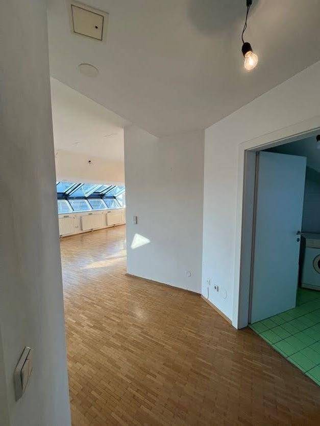 Flur mit Holzparkettboden, weißen Wänden und Zugang zu weiteren Räumen im Dachgeschoss.