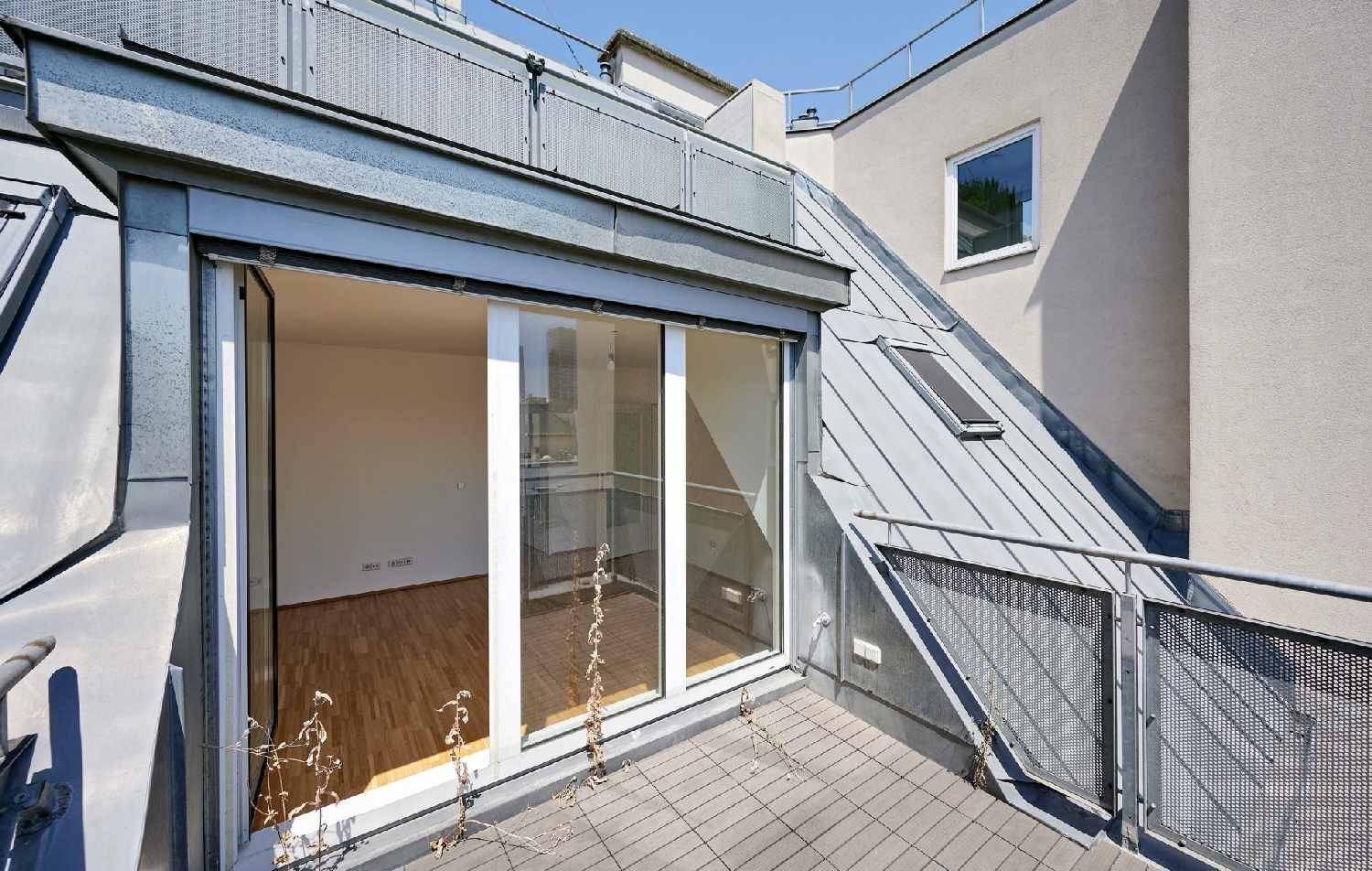 Dachterrasse mit Metallgeländer und Blick auf die umliegenden Gebäude der Stadt.