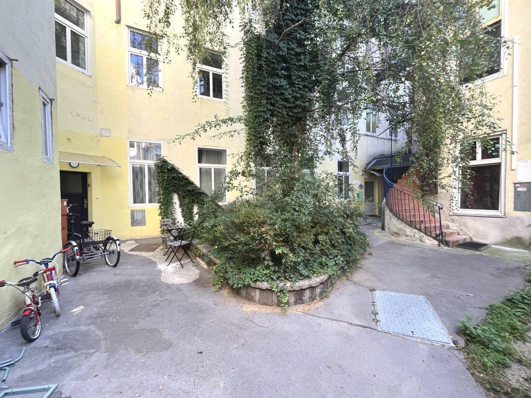 Begrünter Innenhof mit Sitzgelegenheiten und Fahrradabstellplätzen, umgeben von Gebäuden.