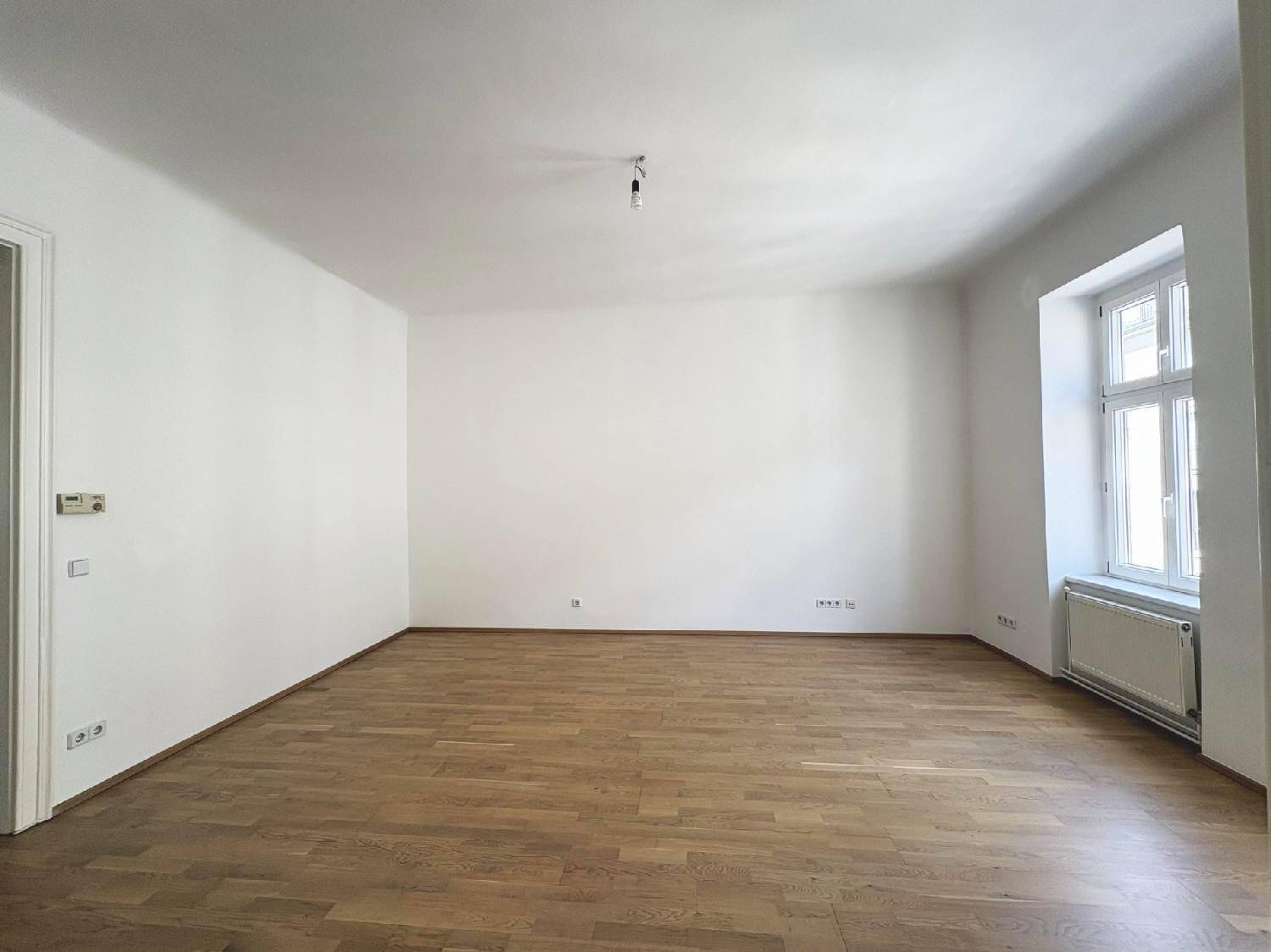 Geräumiges Zimmer mit großen Fenstern und hellem Holzfußboden, ideal für individuelle Gestaltung.