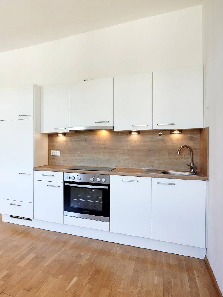 Detailansicht einer modernen, weißen Küchenzeile mit Holz-Arbeitsplatte und integrierten Geräten.
