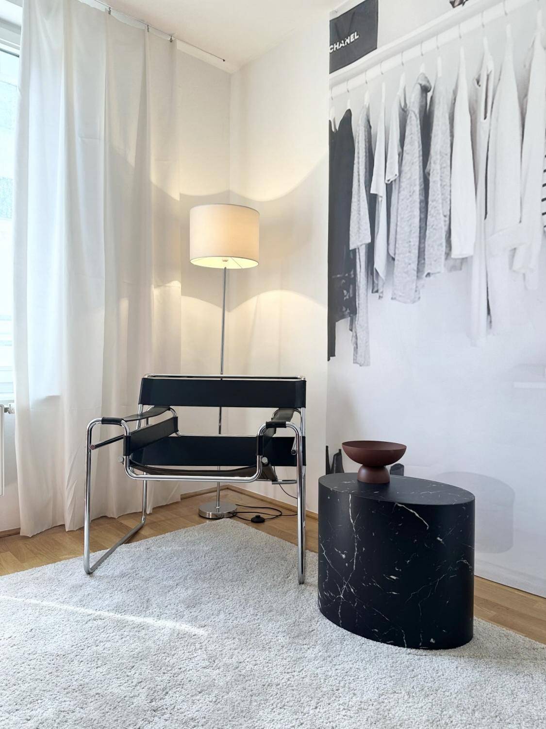 Heller Raum mit modernem Sessel, Stehlampe und großformatigem Wandbild.
