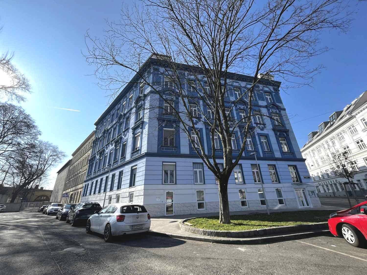 Historisches Gebäude mit auffälliger blauer Fassade und vielen Fenstern an einem sonnigen Tag.