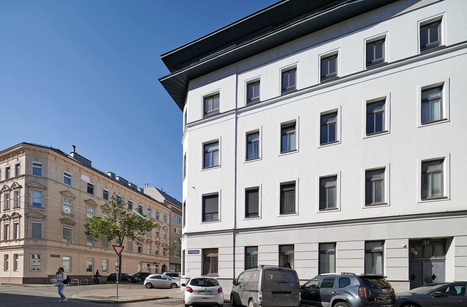 Detailansicht der Gebäudeecke mit modernen Fenstern und der umliegenden städtischen Architektur.