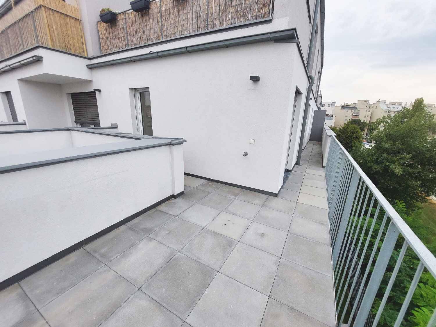 Geräumige Terrasse mit Fliesenboden und Blick auf die umliegenden Gebäude und Grünflächen.