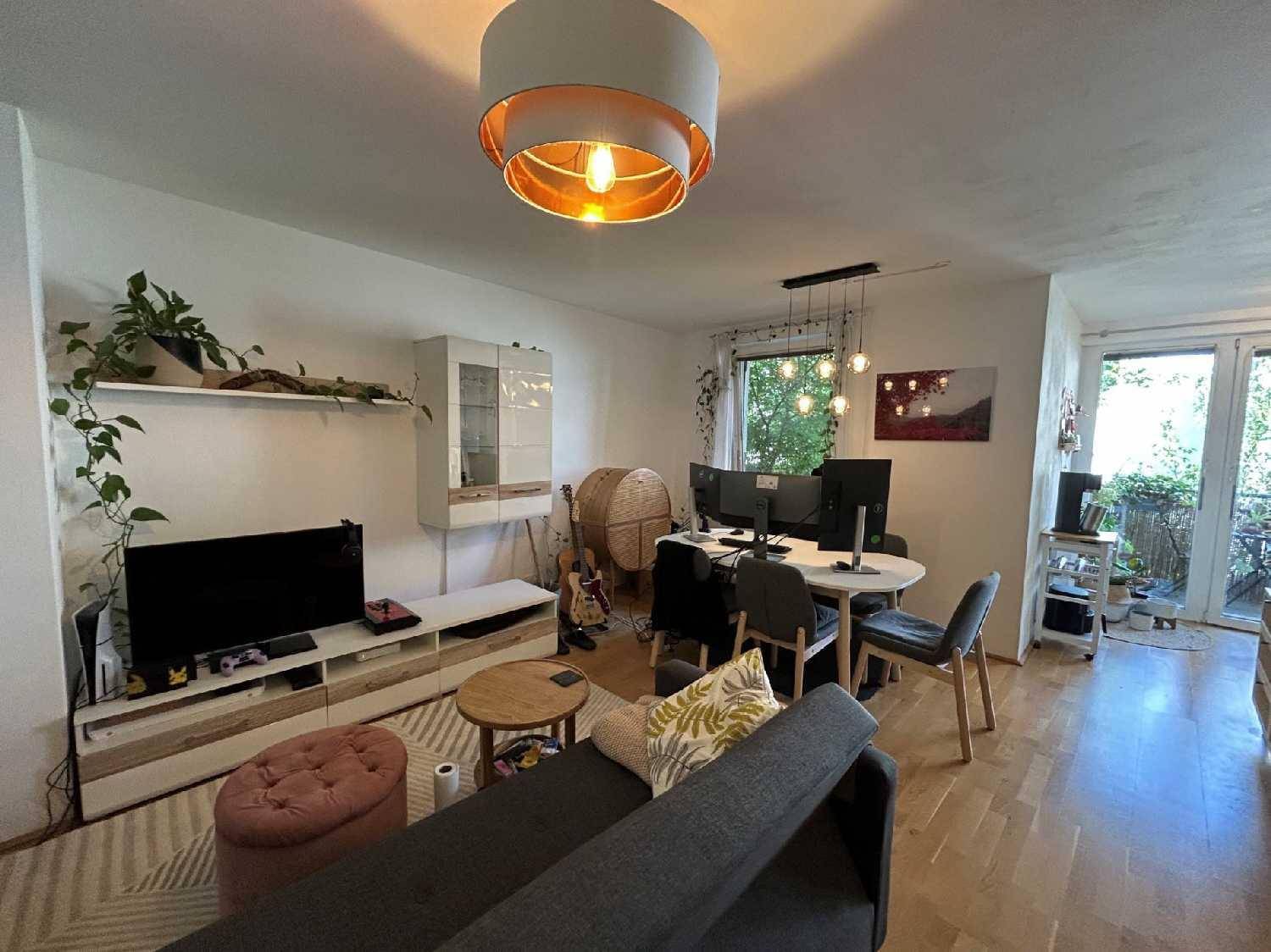 Heller Wohnbereich mit Esstisch, Arbeitsplatz und Zugang zu einem Balkon.