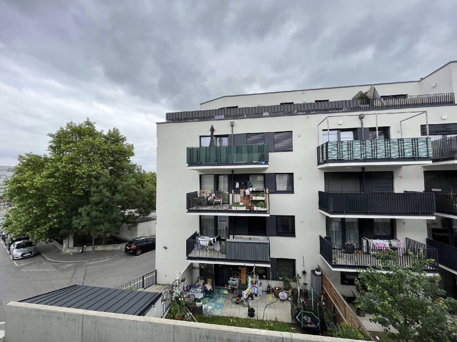 Moderne Wohnanlage mit mehreren Balkonen und begrünten Außenbereichen unter bewölktem Himmel.