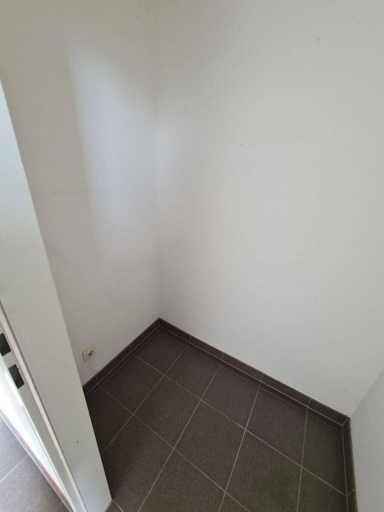 Kleiner, leerer Eckbereich mit dunklen Fliesen, nutzbar als Abstellfläche.