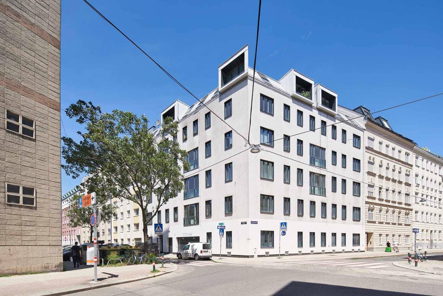 Modernes Eckgebäude mit vielen Fenstern an einer belebten Straßenkreuzung.