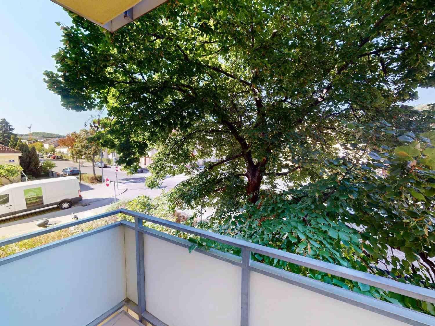 Balkon mit Blick auf die Straße und umliegende Bäume, bietet eine grüne Aussicht.