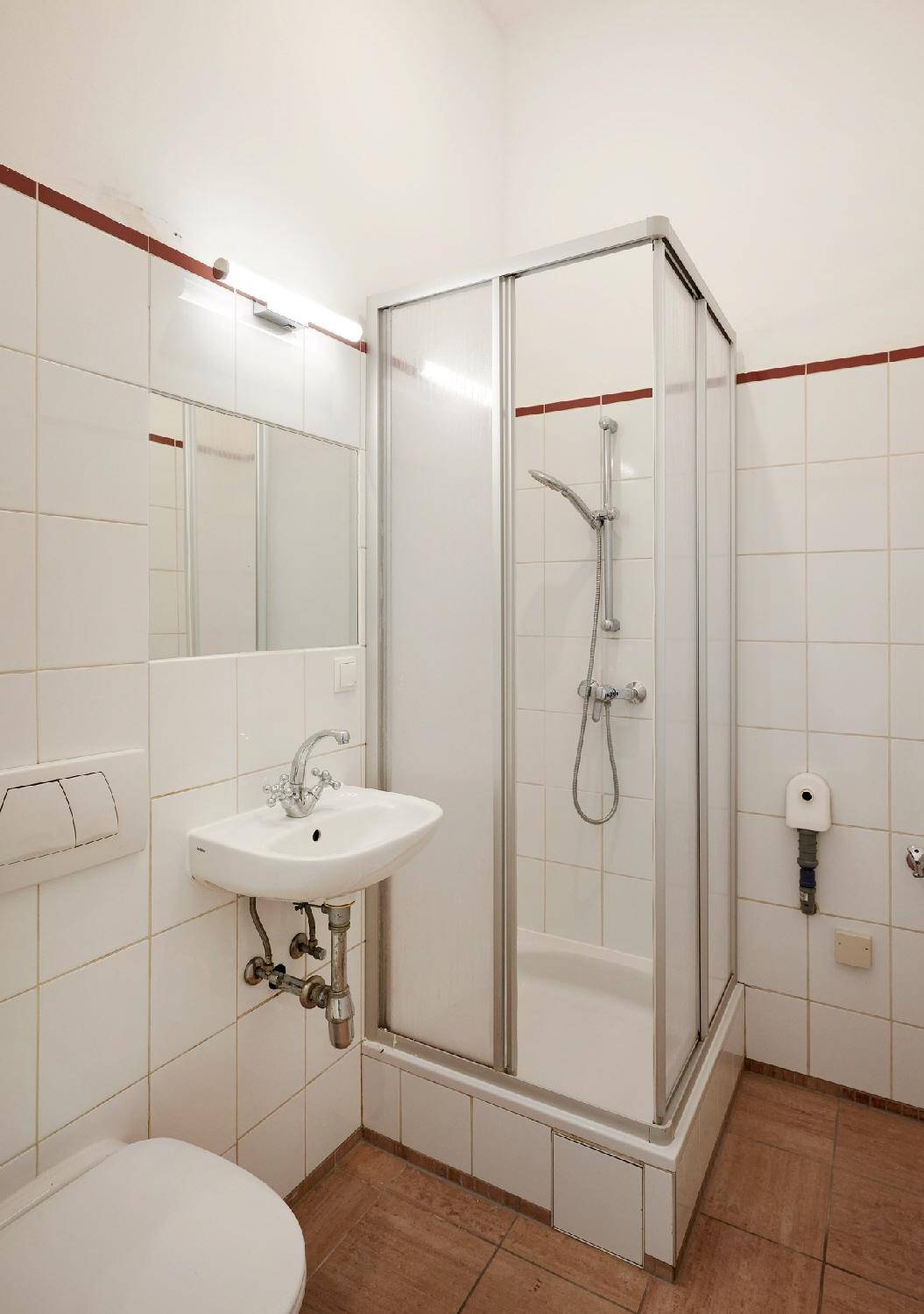 Kompaktes Badezimmer mit Duschkabine, WC und Waschbecken, ausgestattet mit weißen Fliesen.
