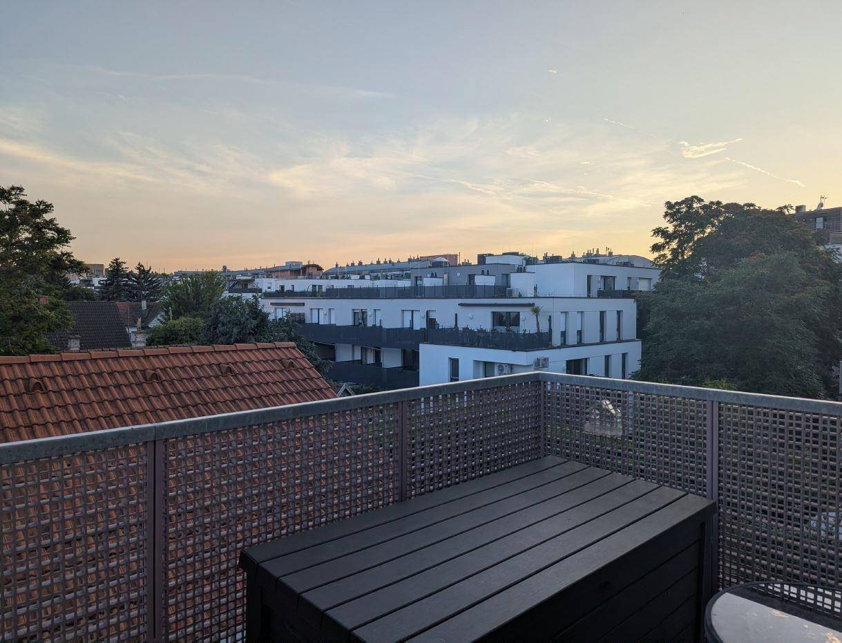 Weitblick vom Balkon über die umliegenden Gebäude und Dächer bei Abenddämmerung.
