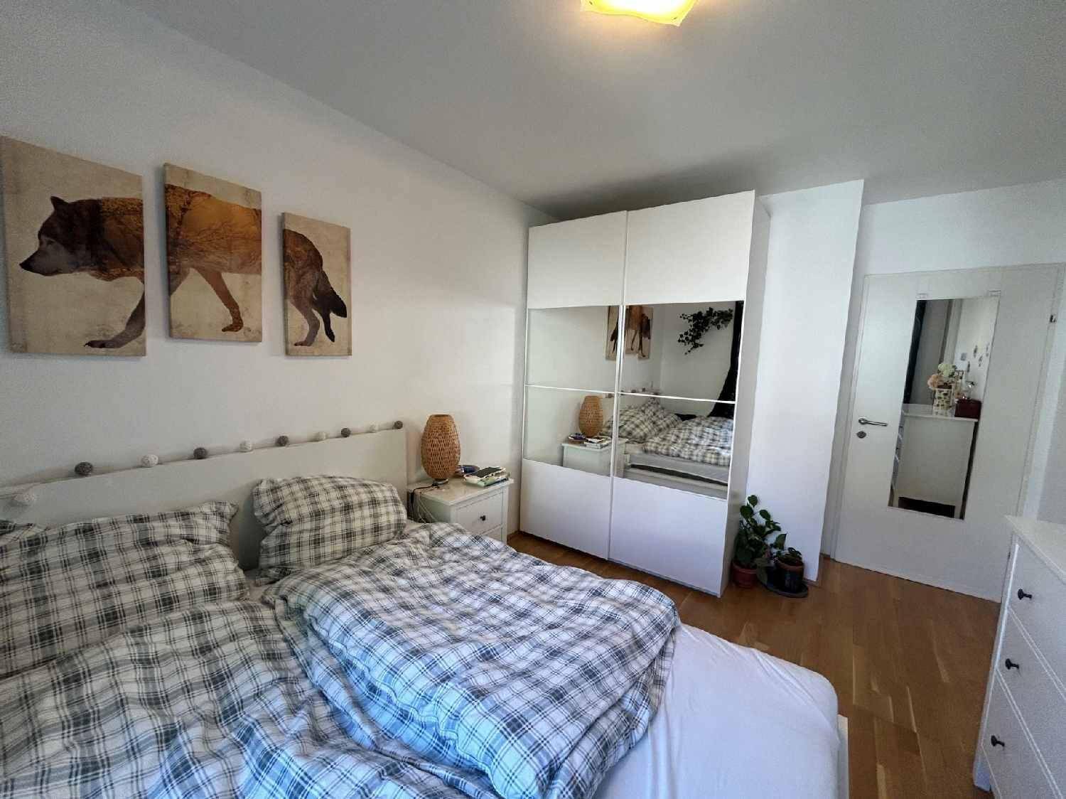 Schlafzimmer mit weißem Kleiderschrank, Doppelbett und hellem Holzboden.