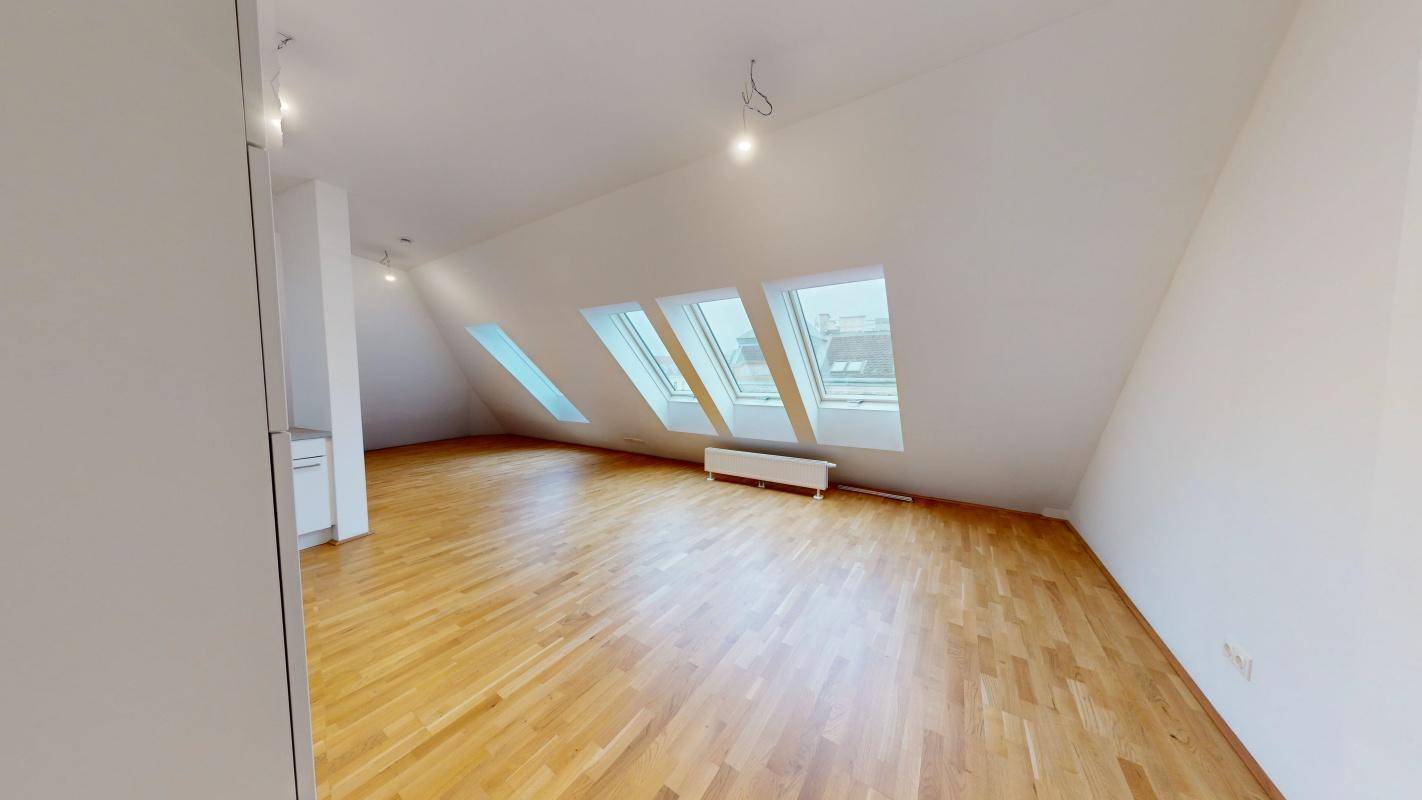Heller Dachgeschossraum mit Holzboden und schrägen Wänden, ideal als Wohnbereich.